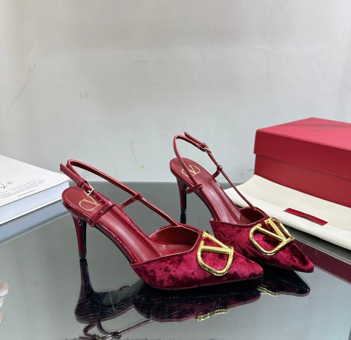 Burgundy red heels with a gold logo on the toe